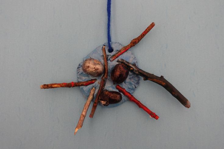 Clay mobile with painted acorns and sticks.