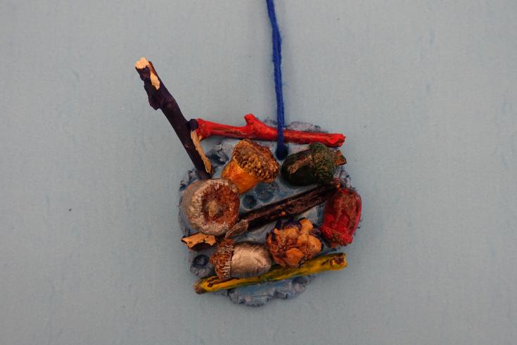 Clay mobile with painted acorns and sticks.