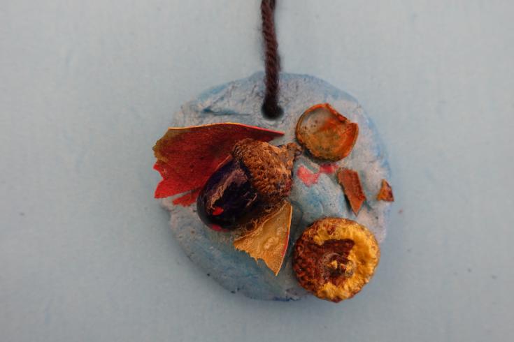 Clay mobile with painted acorns and wood chips.