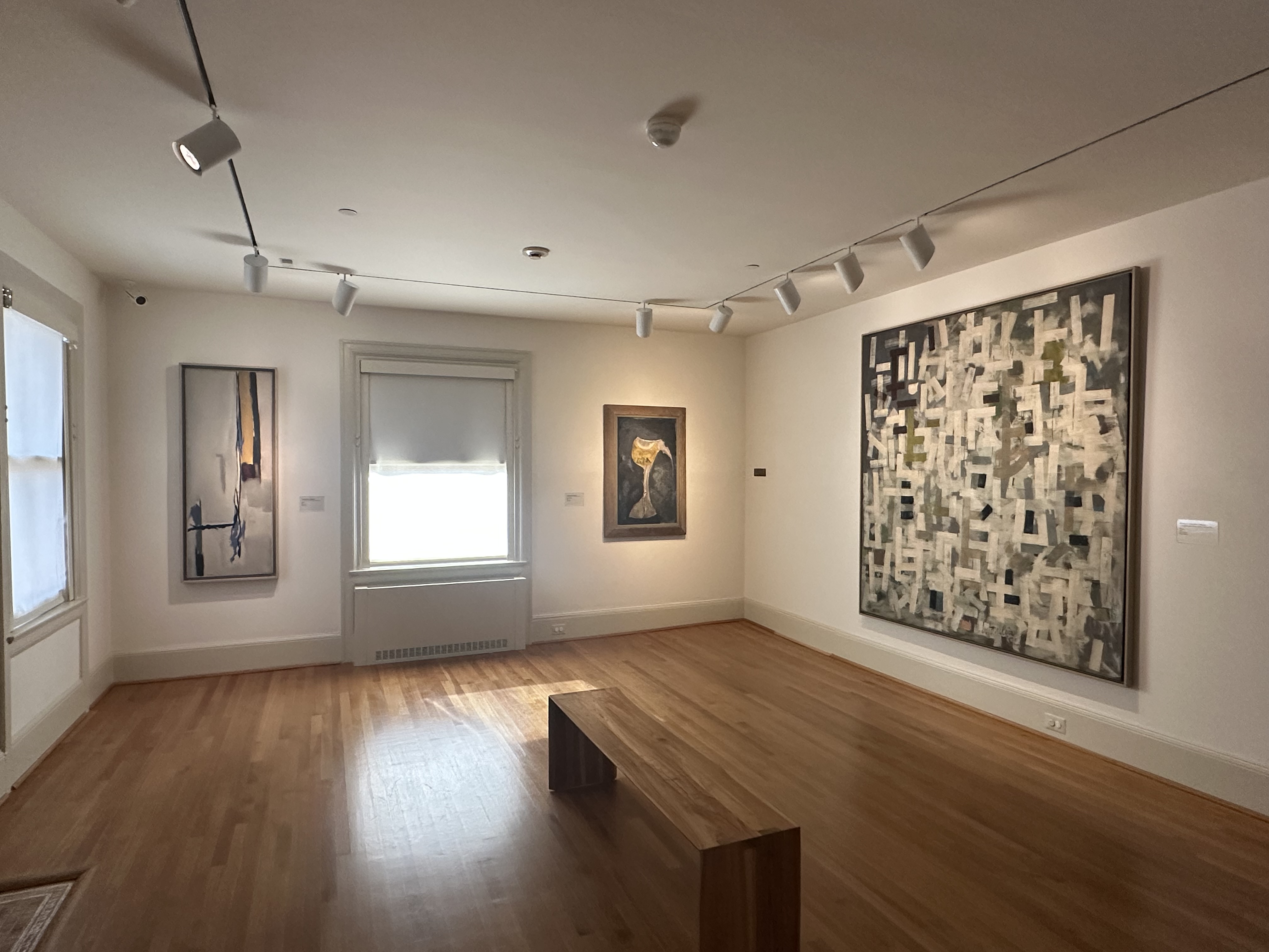 Installation photo of Gallery D with three artworks on the wall and large windows
