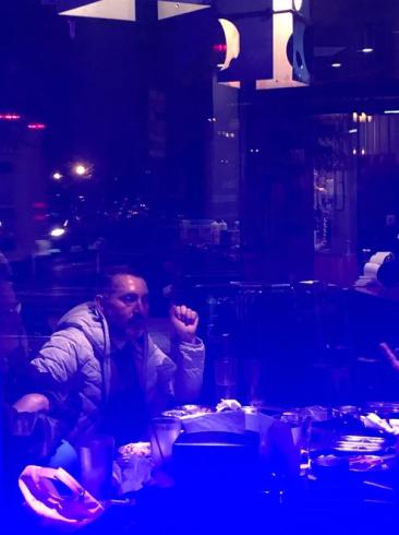 Photograph with a blue tint of a man sitting at a table