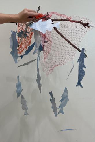 Photograph of someone holding a mobile artwork made of paper and branches