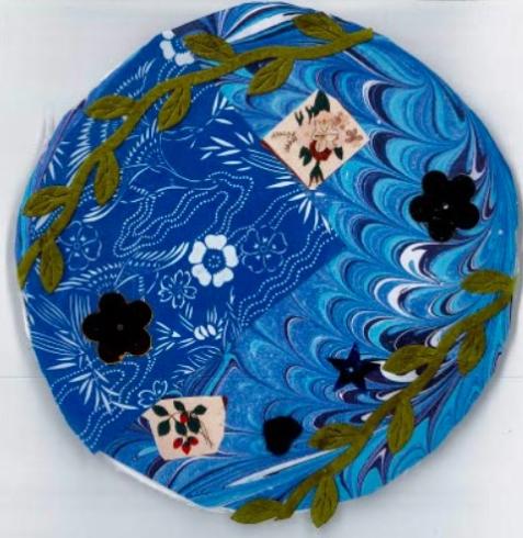 Circle with collage of blue materials and green vines.