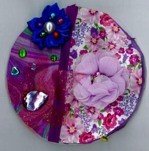Circle with collage of purple materials and flowers.