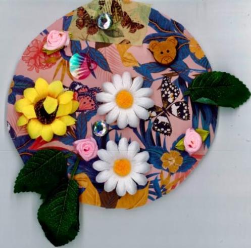 Circle with collage of a variety of flowers and animals on pink paper.