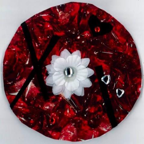 Circle with collage of red materials and a white flower.