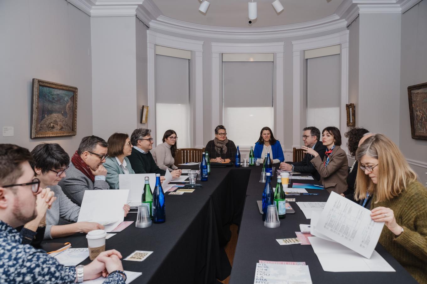 A group of people sitting around two rows of tables having a meeting